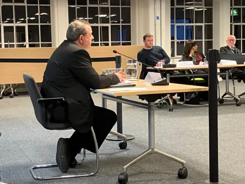 South Leicestershire Conservative MP Alberto Costa sitting in front of Harborough District council's planning committee objecting to changes to the Lutterworth East development