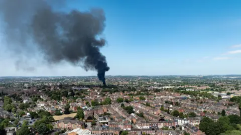 A drone shot of black smoke in the air over a residential area