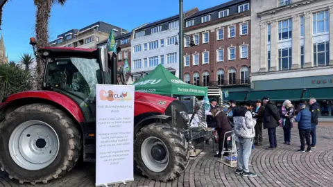 A red tractor and people gathered around a green NFU stall