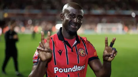 Albert Adomah holds up two fingers on each hand to show Walsall's four goals scored over the two legs of their League Two play-off semi-final win over Chesterfield