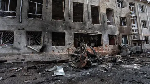 Getty Images This photo taken on August 16, 2024, during a press tour organized by Ukraine, shows a wrecked car next to a destroyed building in the Ukrainian-controlled Russian city of Sudzha, Kursk region, during an attack of Russians in Ukraine.