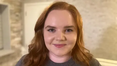 A woman with red hair smiling at the camera