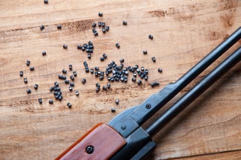 An air rifle and pellets on a wooden background