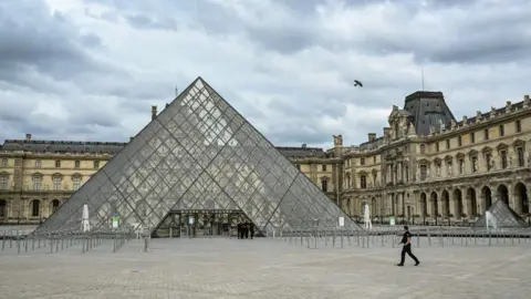 French gendarmes patrol in front of the Musee du Louvre and the Pyramide du Louvre