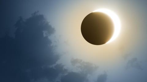 A partial solar eclipse with some dark cloud in the sky