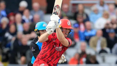 Keaton Jennings batting for Lancashire, with a full flourish of his bat, as the Worcestershire wicketkeeper watches on