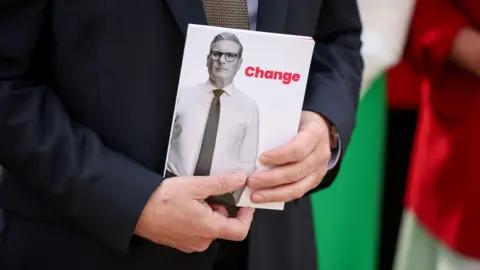 PA Media Close up of Sir Keir Starmer's hands holding manifesto