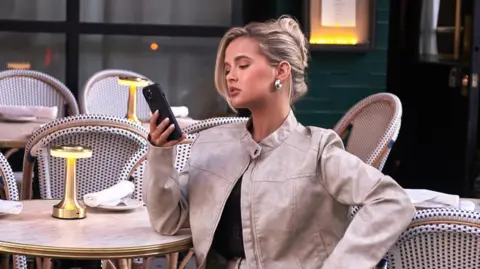 PrettyLittleThing Influencer Molly-Mae Hague looking at a phone during a PrettyLittleThing photoshoot