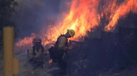 A firefighter battles the flames as fires rage in Southern California 