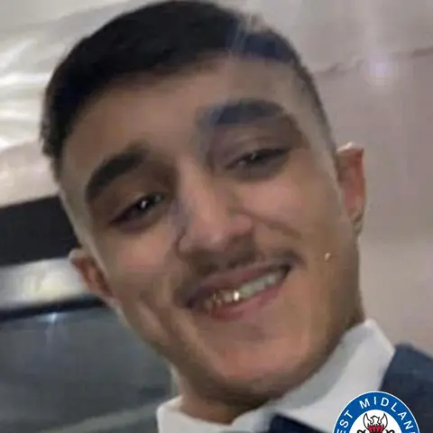 West Midlands Police A man with dark hair and a white collar smiles at the camera, pictured from the shoulders up.