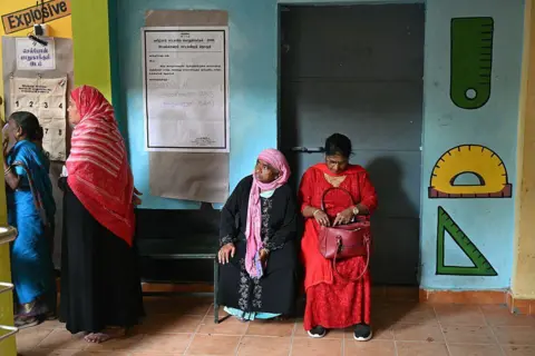 AFP via Getty Images Voters wait to cast their vote outside a polling station during the 2026 Tamil Nadu Legislative Assembly elections 