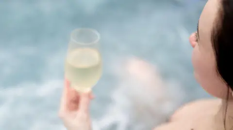 A woman in a hot tub drinking prosecco