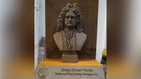 Stoke-on-Trent City Council A bronze bust which will be placed on a plinth. There is a plaque in front of it which reads Glebe Street Works and identifies it as part of the Stoke-on-Trent Living Heritage City trail. The city's centenary logo also appears on the plaque.