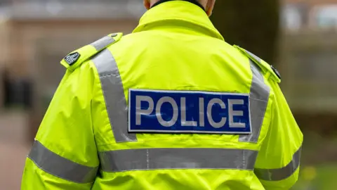 The back of a high-vis police jacket, with the word 'police' written in capital letters across the back. 