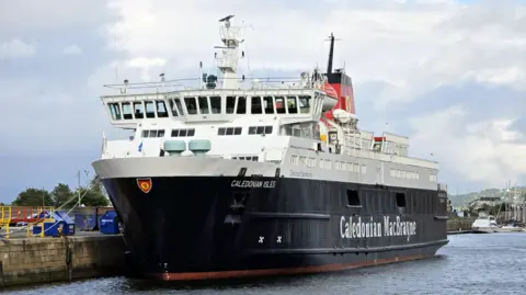 A black and white ship with a red funnel and Caledonian MacBrayne written on the side in white lettering