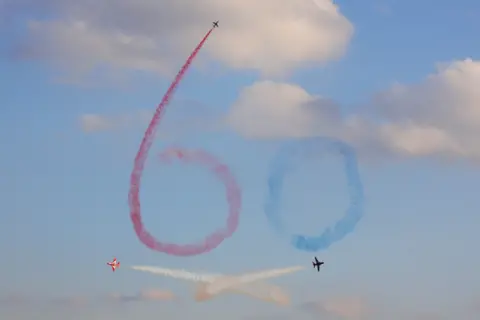 Geoff Matthews Planes writes the number '60' in red and blue in the sky