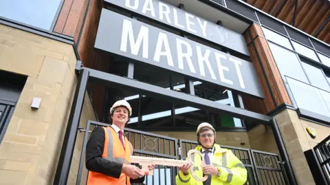 Bradford Council Councillor Alex Ross-Shaw being handed a giant key by Dan Doherty from Kier after the construction phase was completed

