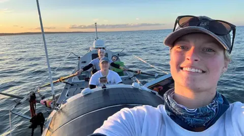 PA Media Lottie Hopkinson-Woolley, Miriam Payne and Jess Rowe in their boat