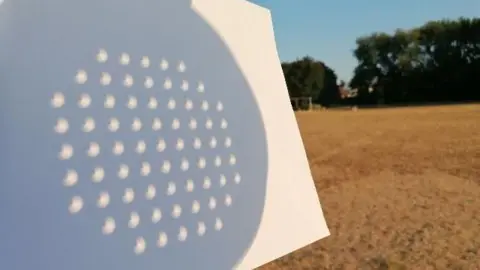 Smiley-Sue The solar eclipse visible through a colander