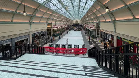 A view from the top of the white and black stairs looking down at the new empty space.