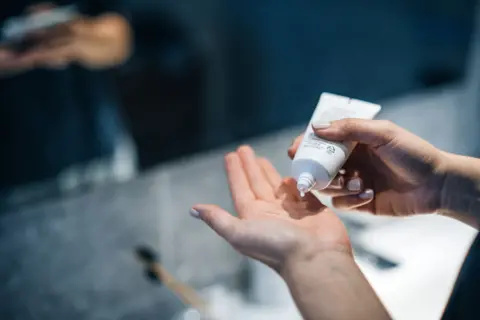 Getty Images Picture of someone putting sun cream on their hands