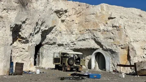 A military vehicle next to a rock face