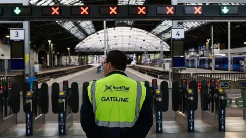 Getty Images rail worker standing at station barriers