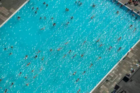jasonhawkes.com Blue swimming pool with people swimming