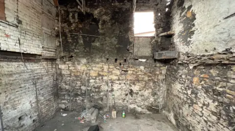 Auction House South Yorkshire A dark room with old stone walls and a concrete floor
