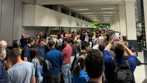 People queuing at Manchester Airport after their flights were cancelled