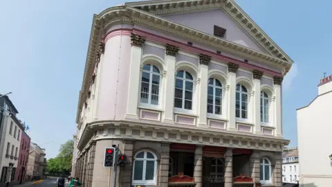 The pink and white States building with columns set into the wall besides large windows.
