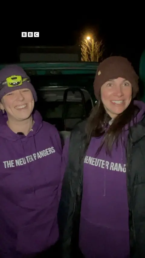 Two women wearing purple tops with The Neuter Rangers written on them.