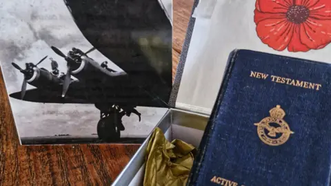 A Bible in a presentation box, beside a photograph of a World War Two Short Stirling bomber and a picture of a poppy.