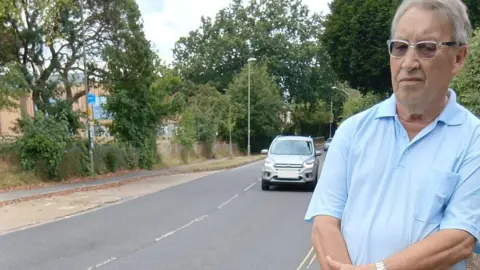 Frank Croton Frank Croton stood beside the road as a car is driving beside him