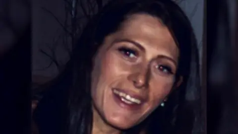 Scottish police officer Sandie Butler, who has dark hair, smiles against a dark background.