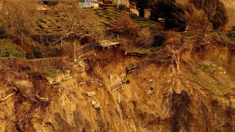 A brown crumbling cliff with a maze visible about 10 metres close to the edge.