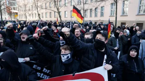 AFP People hold German flags and clench their fists as they take part in a march of extreme right supporters on February 22, 2025 in Berlin, one day before general elections