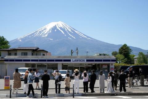 Tourists line up to get take photos of Mt Fuji rising up behind the Lawson store 
