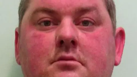 Mugshot of Marc Bear. Bear is a white man. He has a slightly red face and is looking directly into the camera. He is of larger build. He has brown hair.