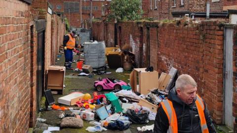 Middlesbrough Council staff clearing fly-tipped rubbish from a back alley