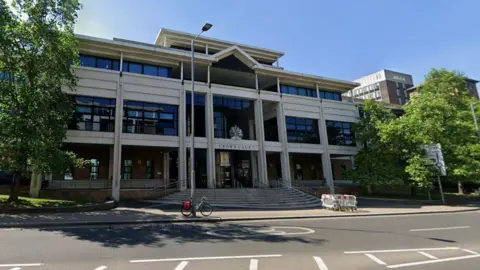 A street view of a court building. There are trees outside the building.