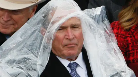 George W. Bush wearing a plastic poncho over his head