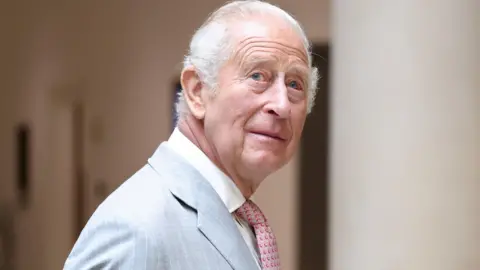King Charles III, who is wearing a light grey suit.