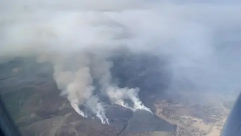 Marie Collins An aerial view of a moorland fire, with smoke seen rising from the ground