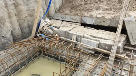 A picture of a building site and the collapsed wall.
