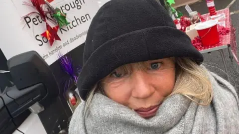 Beccy Tyler Beccy wearing a black Woolly hat and a grey scarf 