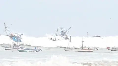 Several fishing boats upended by a huge wave