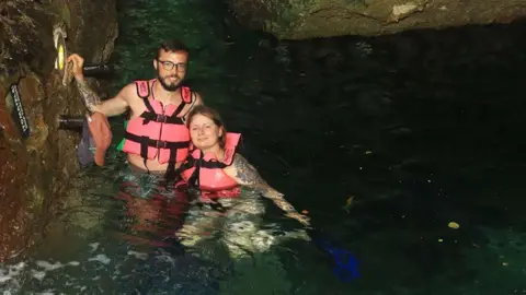 Laura Strang Laura Strang and her husband in the water between rocks wearing flotation devices