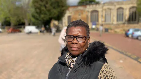 Cheryl Taylor wearing black framed glasses with and animal print top and black body warmer