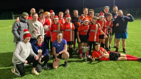 Students and staff at Redbourne Upper School stand to have a team photograph taken with Luton Town's Jordan Clark and Mick Harford. The players are wearing Luton's orange kit 